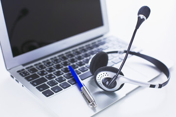 Communication support, call center and customer service help desk. VOIP headset on laptop computer keyboard