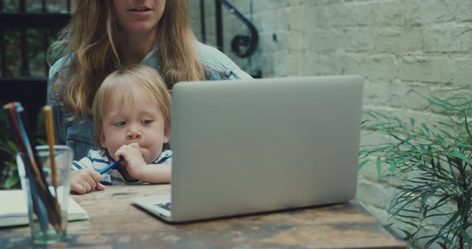 Mother trying to work on laptop with her toddler present
