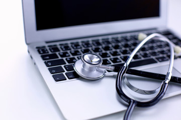 Stethoscope lying on a laptop keyboard in a concept of online medicine or troubleshooting the computer viewed low angle with copy space