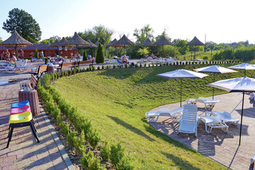 Obraz premium Semicircular strip for holidaymakers laid out with tiles. On umbrellas with straw tops do not stand, like mushrooms after a rain
