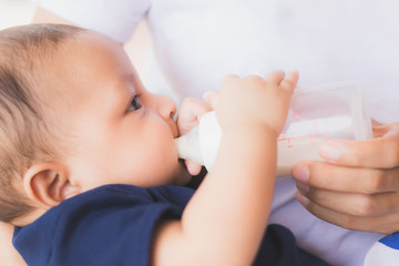 infant baby on being fed by her mother drinking milk from bottle.asian newborn - 213187990