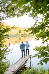 Photo sur Plexiglas Anti-reflet Pêcher Two male friends fishing together standing on the wooden pier during the morning light on the beautiful lake