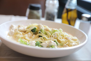 alfredo spaghetti broccoli chicken white sauce in restaurant background