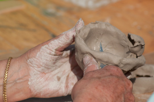 closeup of hands of old woman making clay pottery bowl in outdoor