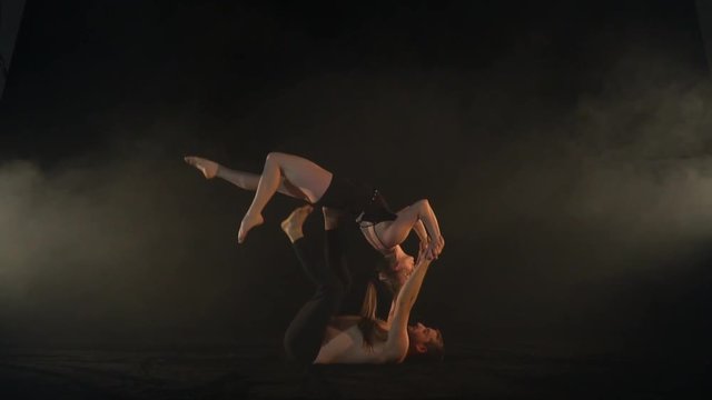 Slow-motion shooting, the man holds the woman upside down, acro yoga in the studio