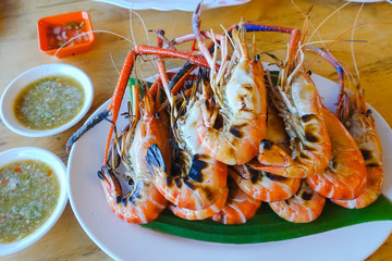 grilled shrimp on dish with spicy seafood saucebrown wooden table background.