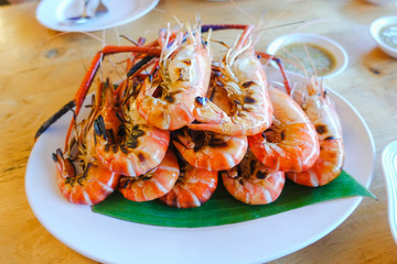 grilled shrimp on dish with spicy seafood saucebrown wooden table background.