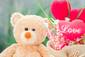cute teddy bear and red love heart in garden for sweet concept and relationship background creative for romantic valentine and birthday style in vintage tone.