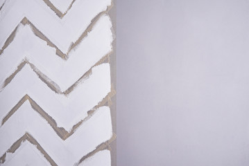 Painting a wall with masking tape. white zigzag strips on grey wall.