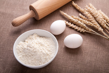 Baking ingredients. Flour, eggs, wheat and rolling pin on  table cloth. Rustic. Copy space