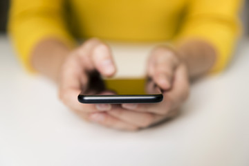Hand of woman using smartphone on white table. Communication and technology concept