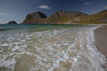 Turquoise sea shore with view to mountains in the Norway at summer time