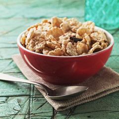 Corn flakes with hazelnuts and chocolate  in red bowl for breakfast on old cyan wooden table