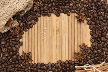Background of coffee beans. Coffee texture. A place to write a text. Cinnamon sticks and cardamom.