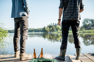Wooden pier with fishing tackles and two bottles with beer near the lake