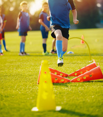 Kid Young Athletes Training with Football Equipment. Football Speed Training. Young Footballer in Blue Sportswear at Training Session on Grass Soccer Field