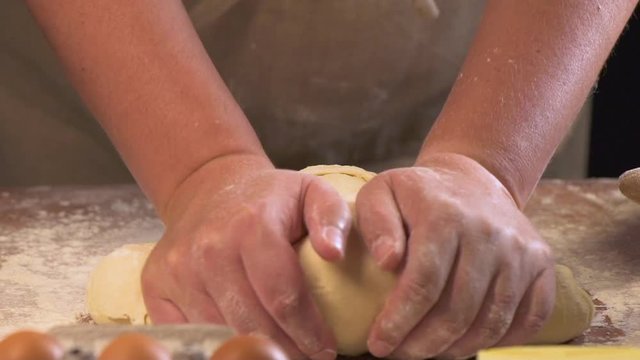
Baker kneading dough in flour on table, slow motion