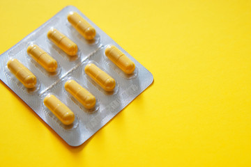 Packing of yellow tablets-capsules on a yellow background