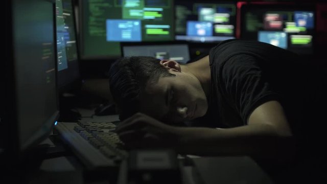 Computer developer and hacker sleeping on his desk at night