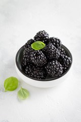 Blackberries in cup, fresh juicy summer berry on a light background, home harvest, garden
