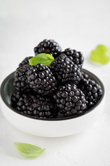 Blackberries in cup, fresh juicy summer berry on a light background, home harvest, garden