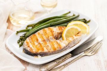 grilled perch with green beans and lemon on white dish
