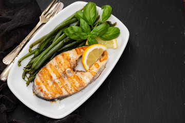 grilled perch with green beans and lemon on white dish