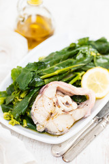 boiled fish with lemon and vegetables on white dish