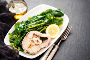boiled fish with lemon and vegetables on white dish