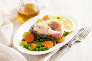 boiled fish with boiled vegetables and lemon on white dish