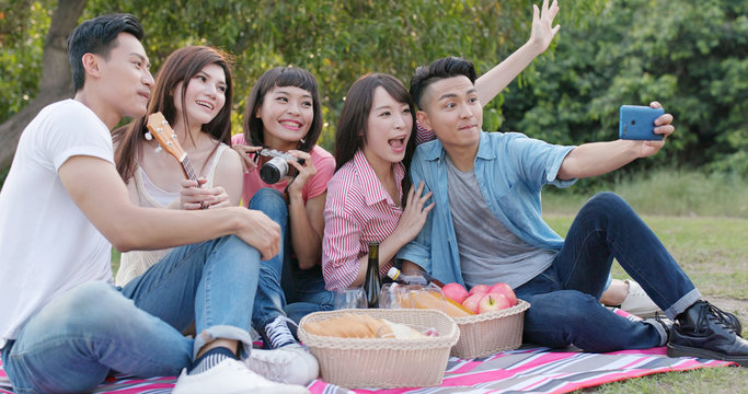 Friends go picnic together in the park and take photo selfie with mobile phone