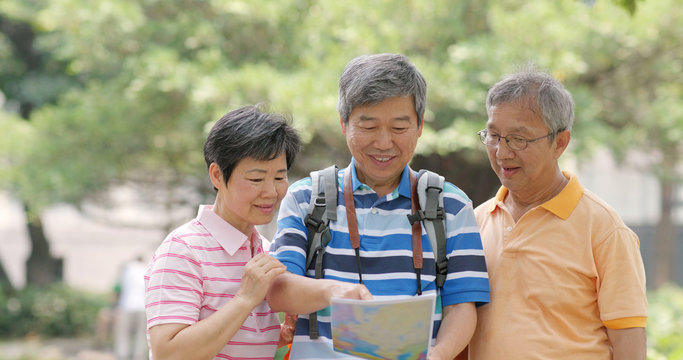 Senior Old Friends Go Travel Together With Backpack, Cellphone And Camera