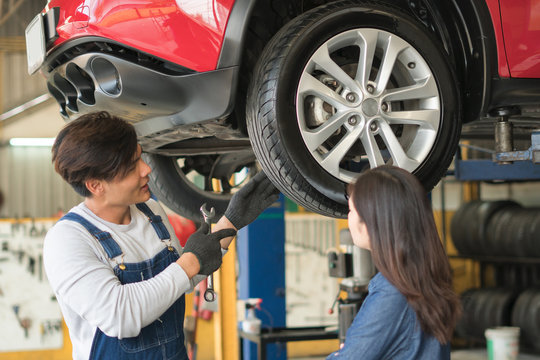 A mechanic showing the tread of a tire to a female customer