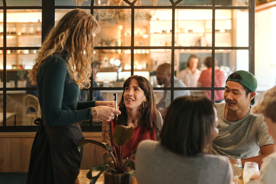 Smiling Group Of Friends Ordering Food In A Bistro