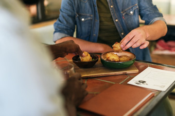 Two men sitting at a bistro table sharing delicious food 