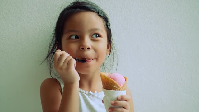 Little girl standing eating ice cream and showing very happy face