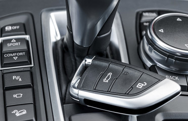Closeup inside vehicle of wireless key ignition. Start engine key. Car key remote in black perforated leather interior. Modern car background. Modern car Interior details. Car detailing.