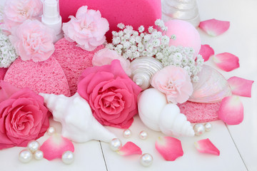 Cleansing spa beauty treatment products with pink roses and carnation flowers, shell shaped soaps,...