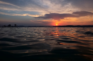 sunset over lake Balaton - golden bridge, calm water, close up, hills in background