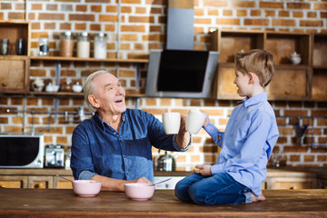 Cule little boy drinking tea with his gramdfather