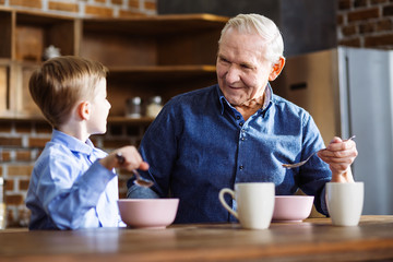 Happy boy and his grandfather enjoying their breakfast