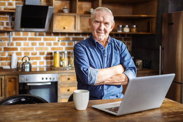 Pleasant eldelry man standing in the kitchen