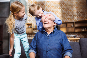 Positive little boy closing eyes of his grandfather