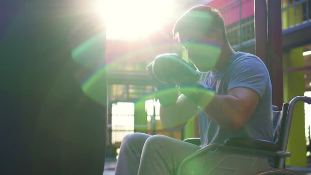 Portrait of a disabled Man in a wheelchair beats a Boxing bag in the gym,close up.Slow mo