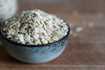healthy living with organic oats for porridge in heap in ceramic bowl on wooden table