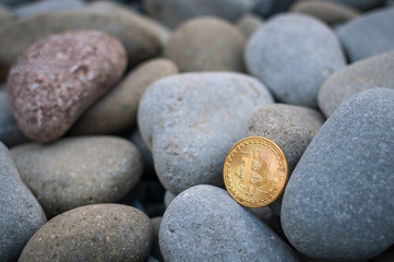 Fototapeta na wymiar Cryptocurrency on the shore among the big sea stones
