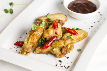 Grilled baked chicken wings with chili pepper and hot sauce on white plate