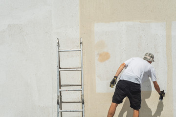 A street artist paints graffiti on the wall. Abstract image of modern art.