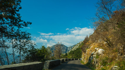 Fototapeta premium Mountain road with sharp turns, old brick fence and vegetation on the sides