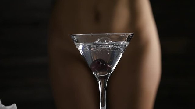 sexy young woman in a white panties prepares a cocktail with cherry in a dark. close-up buttocks and hip. slow motion